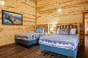 Cozy up in your rustic log bedroom featuring two comfortable beds with charming wildlifethemed linens and warm wood walls that create the perfect mountain retreat atmosphere.
