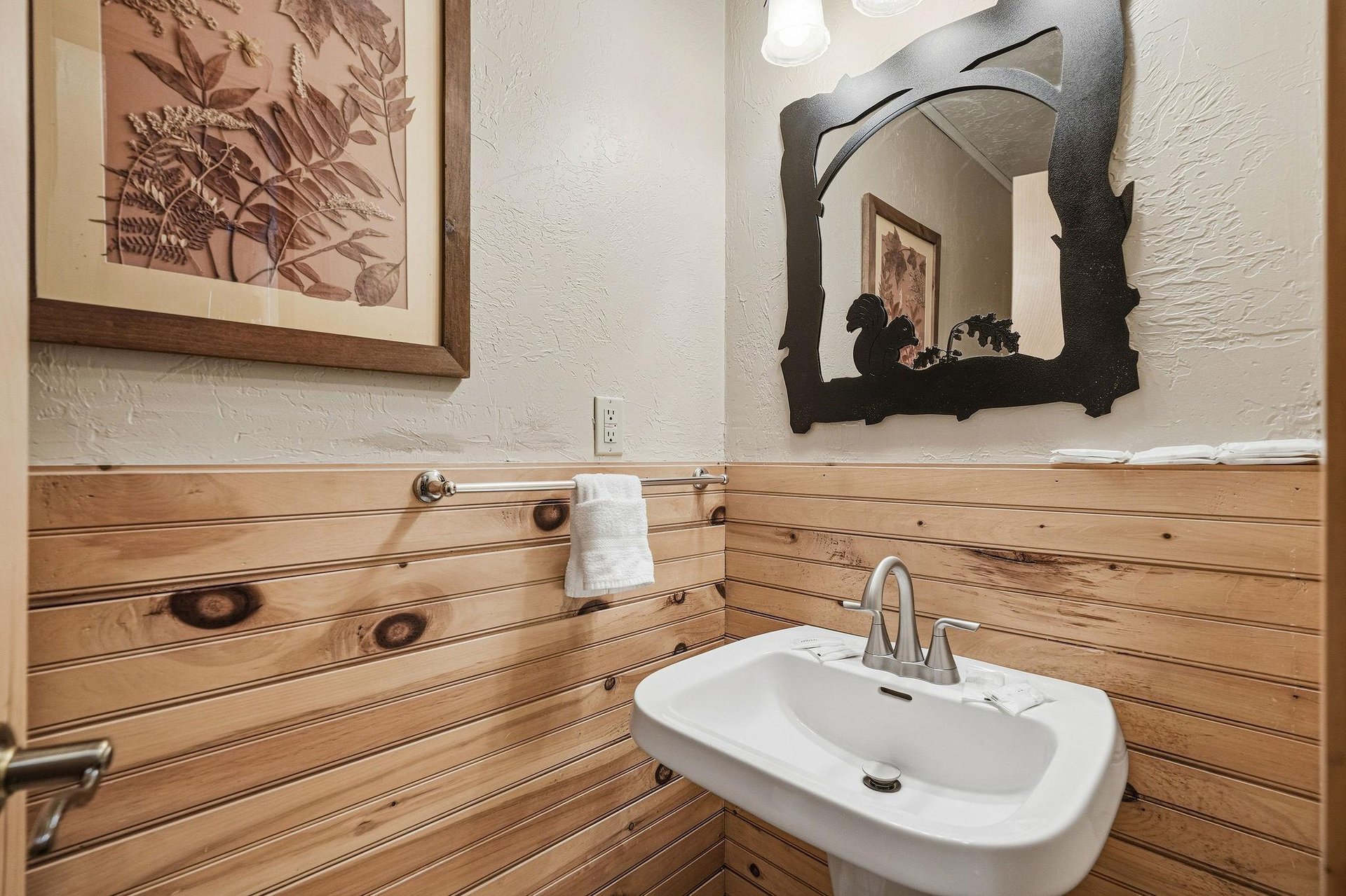 Freshen up in your charming rustic bathroom with warm wood paneling, natureinspired art, and modern amenities for comfort.