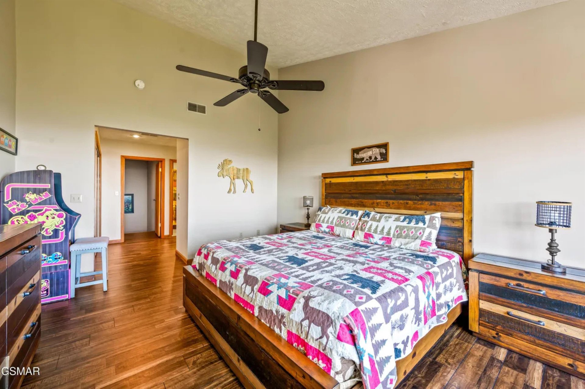 Unwind in your cozy bedroom featuring rustic wooden furniture, a ceiling fan for comfort, and charming decor that creates a warm, welcoming retreat.