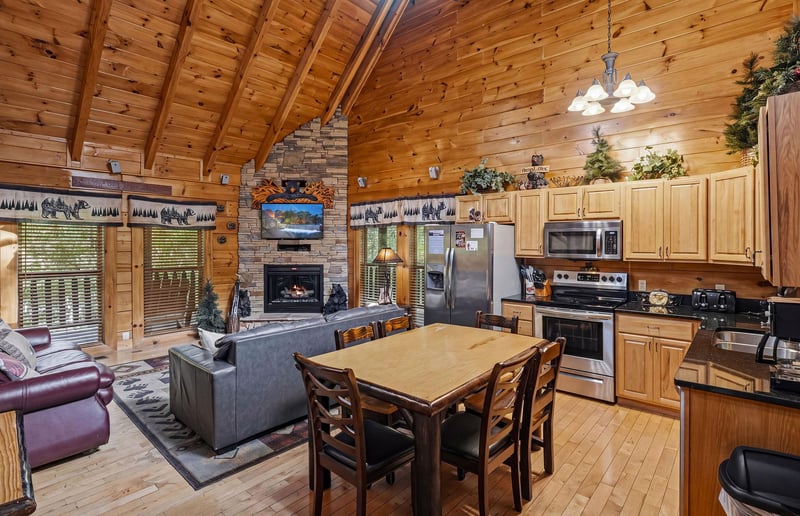 Relax in your rustic cabins open living space, where vaulted ceilings meet stone fireplace warmth and a fullyequipped kitchen awaits your culinary adventures.