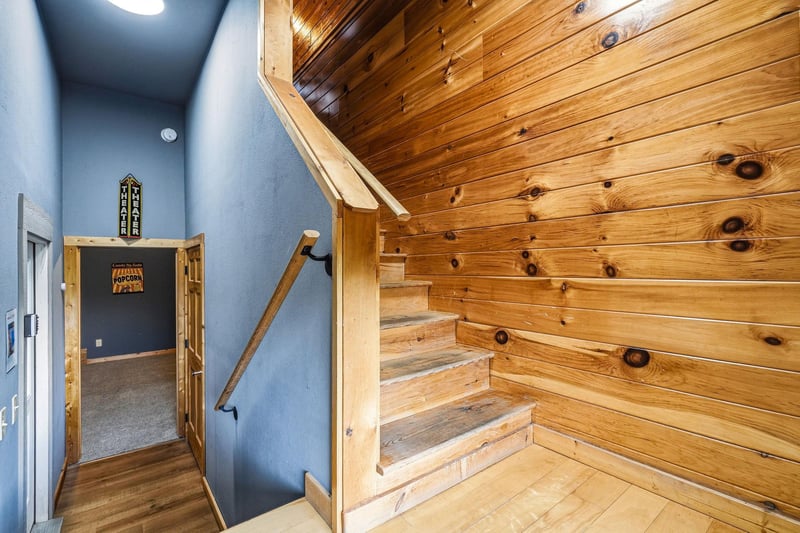 Warm wooden stairs lead you upward in this charming multilevel space, where rustic knotty pine meets cool blue walls—a cozy blend of natural textures and inviting color.