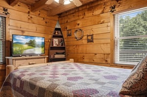 Unwind in your cozy, rustic bedroom with warm wood walls, a plush quilttopped bed, and charming mountain touches. Natural light streams in through your window, framing peaceful treelined views that 