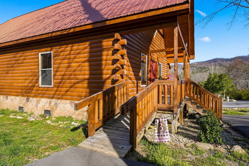 Charming log cabin with mountain backdrop, featuring rustic wooden architecture and welcoming covered porch in scenic natural setting.