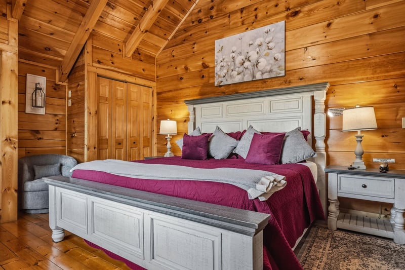 Rest easy in your cozy cabin bedroom, where warm wood beams and elegant furnishings create a peaceful mountain retreat.