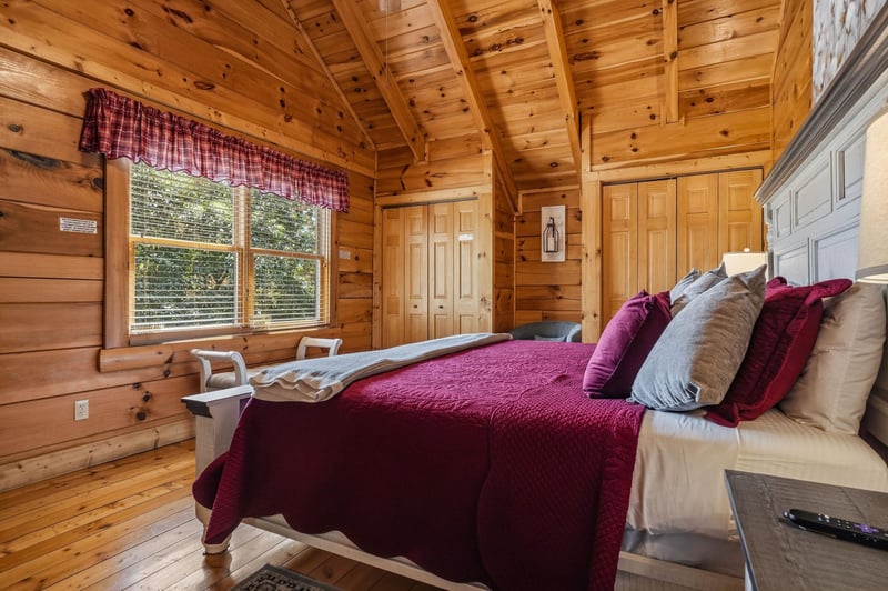 Sink into plush comfort beneath soaring pinebeamed ceilings, where natural light streams through the window and warm wood surrounds your peaceful retreat.