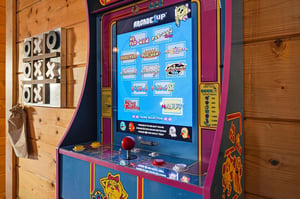 Challenge friends or family to a game of tictactoe before diving into classic arcade fun with a nostalgic gaming cabinet featuring PacMan and other retro favorites.