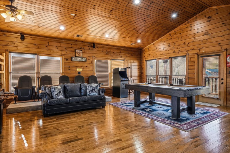 Step into your spacious game room where warm wood surrounds you, inviting friendly competition at the pool table or relaxed evenings on the plush leather sofa.