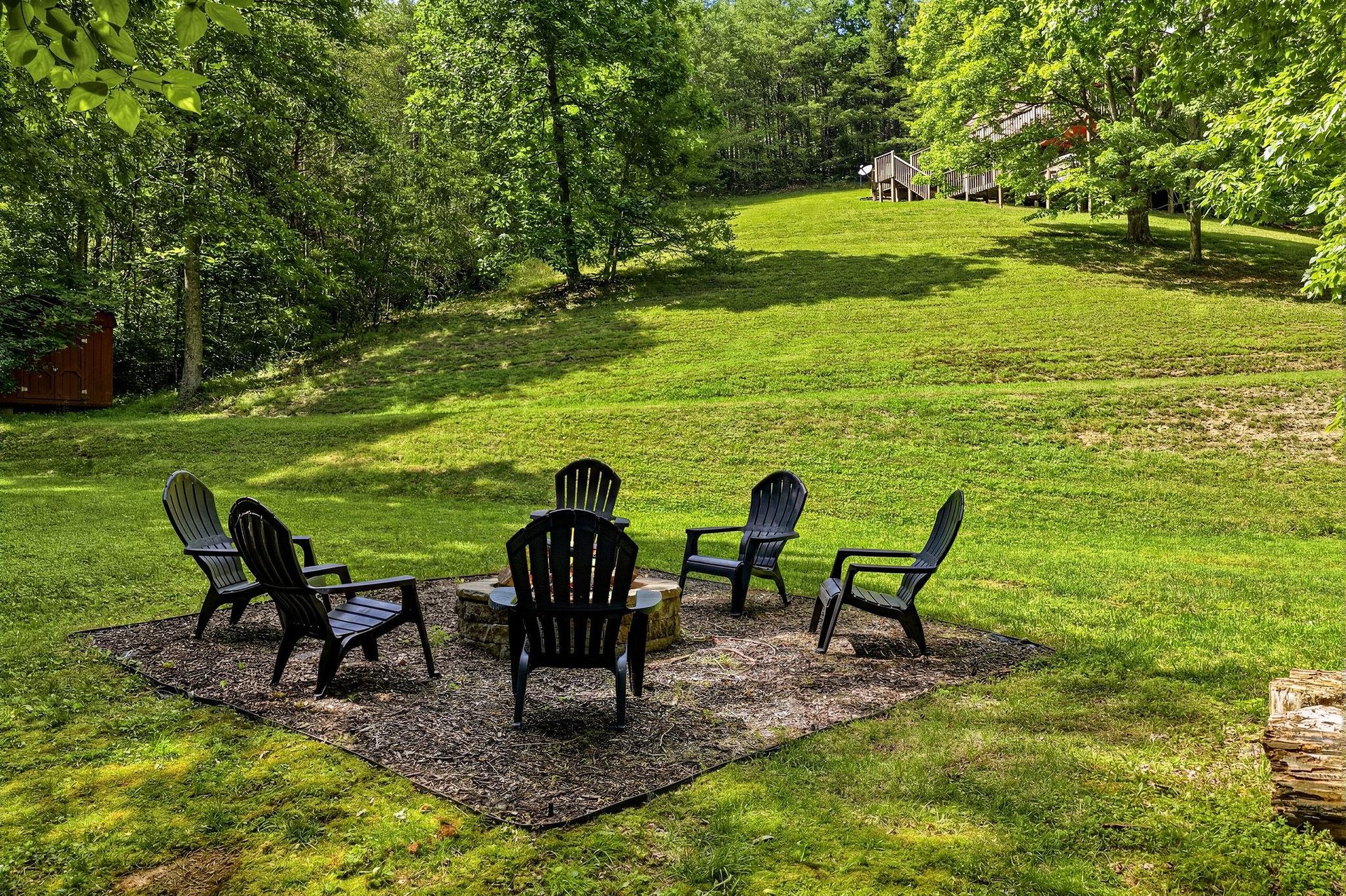 Picture yourself unwinding around this fire pit, surrounded by lush trees and open lawn—a perfect spot for evening conversations and making memories under the stars.