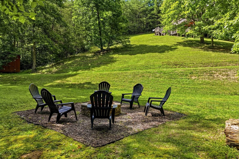 Picture yourself unwinding around this fire pit, surrounded by lush trees and open lawn—a perfect spot for evening conversations and making memories under the stars.