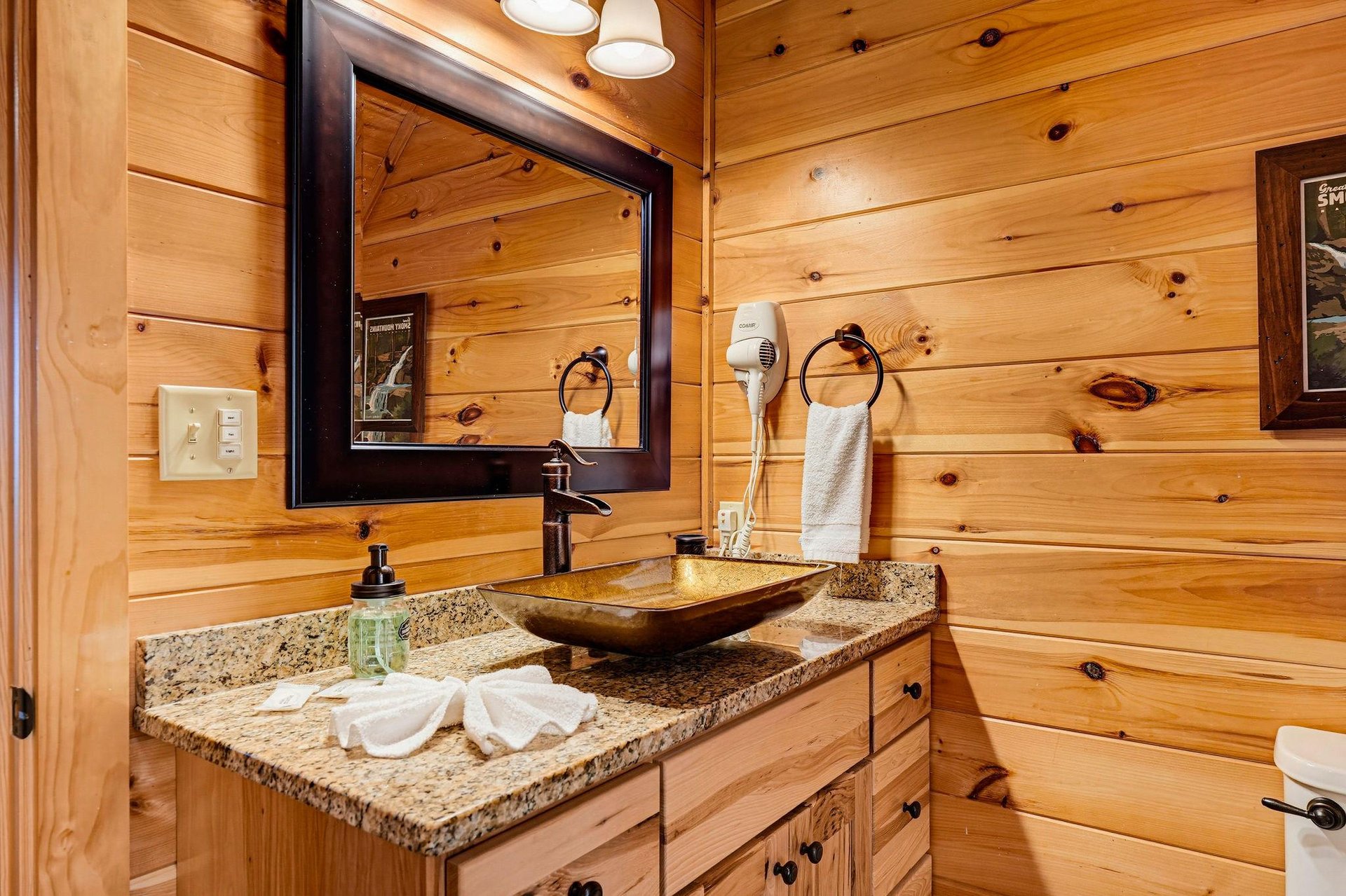 Freshen up in your cabinstyle bathroom, where rustic wood walls and granite countertops blend warmth with modern comfort.
