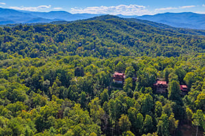 Secluded rental cabins nestled in a vast expanse of lush forest with sweeping mountain ranges creating a stunning natural backdrop.