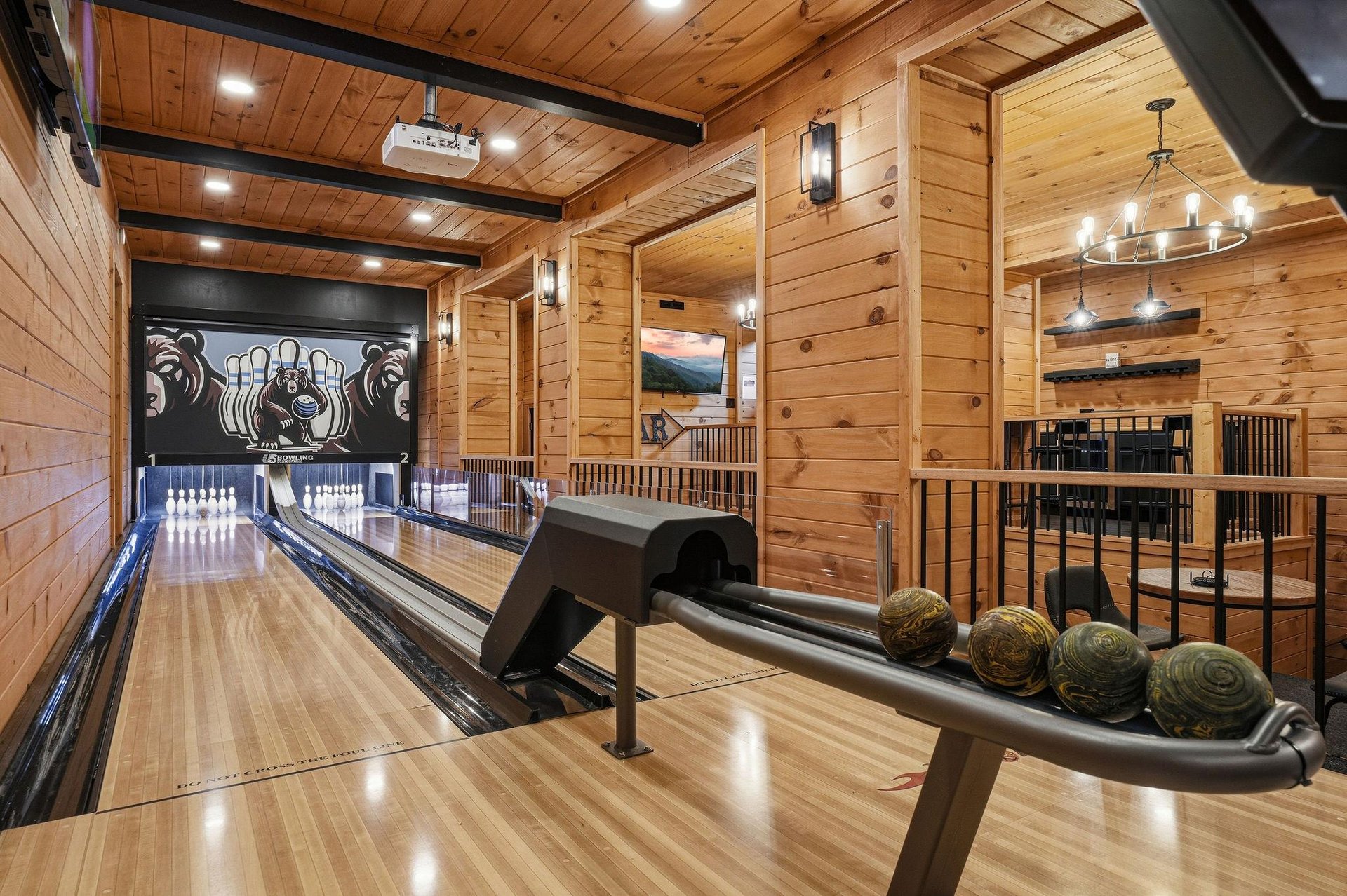 Your private bowling alley awaits, complete with rustic wood beams, warm lighting, and custom scoring displays—grab a ball and let the fun begin in your own mountain retreat.