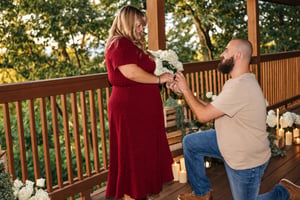 A romantic moment unfolds on a private deck surrounded by lush greenery, capturing a special milestone in a scenic, intimate setting.