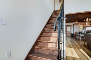Warm wood stairs lead you to the upper level, where cozy spaces await your arrival.