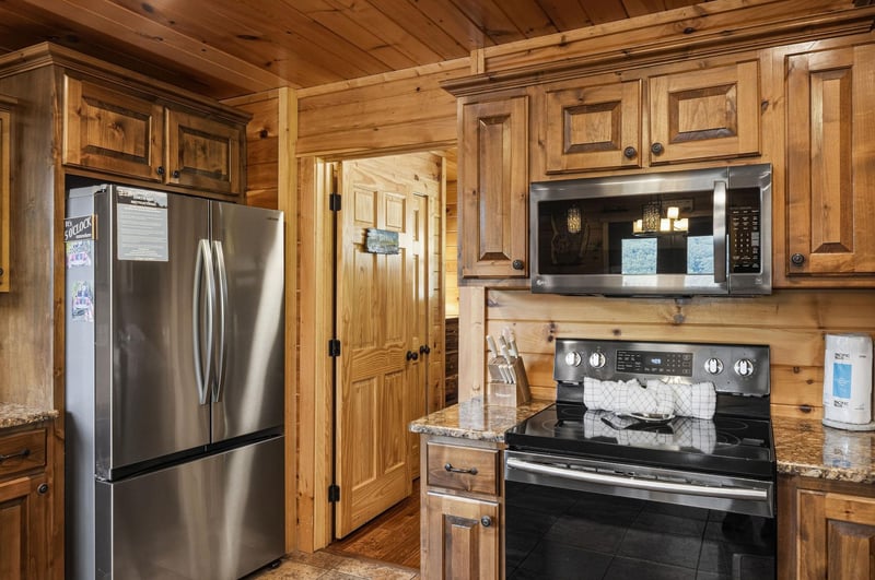 Cook your favorite meals in this fully equipped kitchen featuring stainless steel appliances, granite countertops, and warm wood cabinetry. Modern conveniences meet rustic charm in this inviting space