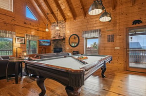 Step into your cozy mountain retreat with soaring woodbeamed ceilings, a stone fireplace, and a pool table ready for friendly competition.