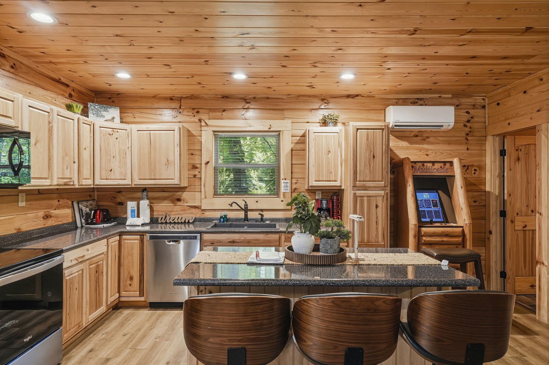 Gather in your spacious cabin kitchen with granite counters, stainless appliances, rustic pine cabinetry, and island seating—perfect for cooking meals together and making memories during your mountain