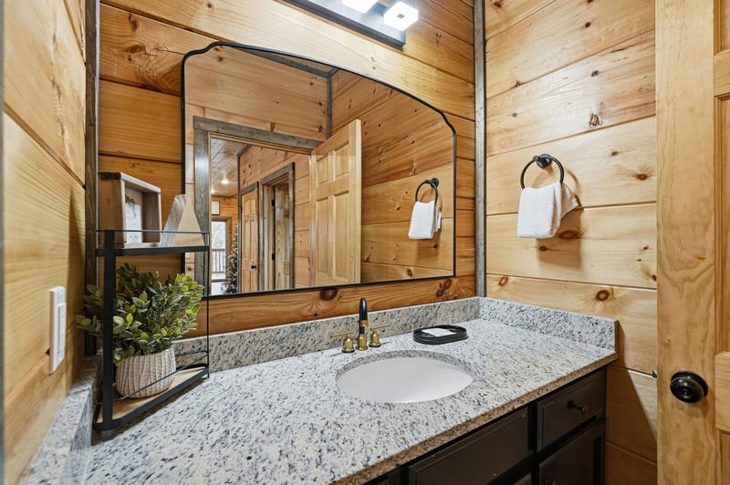 Step into your rustic bathroom where warm cedar walls and granite countertops create a cozy mountain retreat atmosphere.