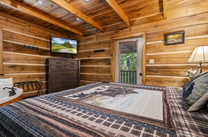Step into your rustic cabin bedroom, where warm wood surrounds you and plaid bedding invites you to unwind. Your private balcony and TV await after days of mountain adventure.