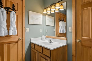 Step into your private bathroom retreat with warm wood cabinetry, soft lighting, and plush towels waiting for your mountain getaway.