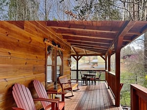 Picture yourself unwinding on this cozy covered deck, surrounded by warm wood tones and peaceful wooded views, with plenty of space for morning coffee or evening meals under the open beams.