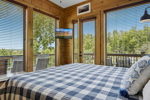 Wake up surrounded by floortoceiling windows in your cozy bedroom, where warm wood walls frame stunning treetop views that make every morning magical.