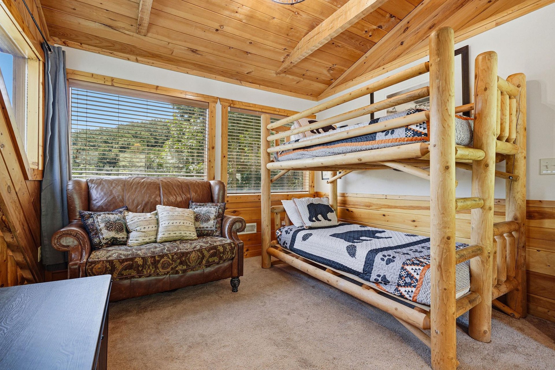 Your cozy rustic bedroom features handcrafted log bunk beds and warm woodpaneled walls and ceilings, creating a charming mountain retreat perfect for family adventures.