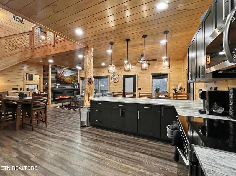 Step into your spacious mountain retreat where modern luxury meets rustic charm. Dark cabinets and marble countertops create the perfect cooking space.