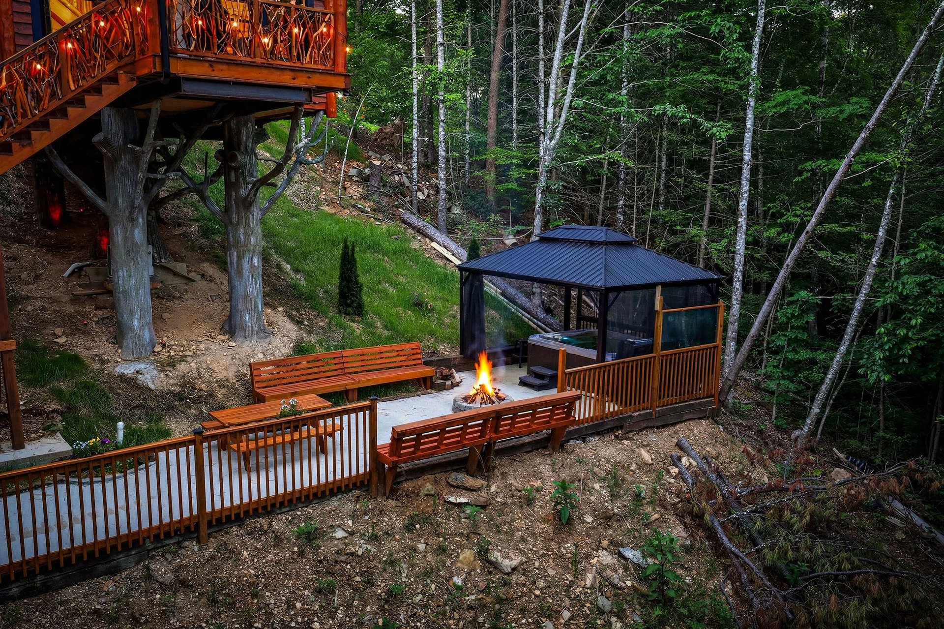 A peaceful woodland retreat featuring a custom fire pit surrounded by handcrafted benches, where you can unwind beneath the trees and enjoy cool forest evenings.