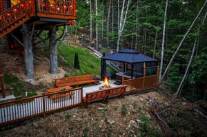 A peaceful woodland retreat featuring a custom fire pit surrounded by handcrafted benches, where you can unwind beneath the trees and enjoy cool forest evenings.