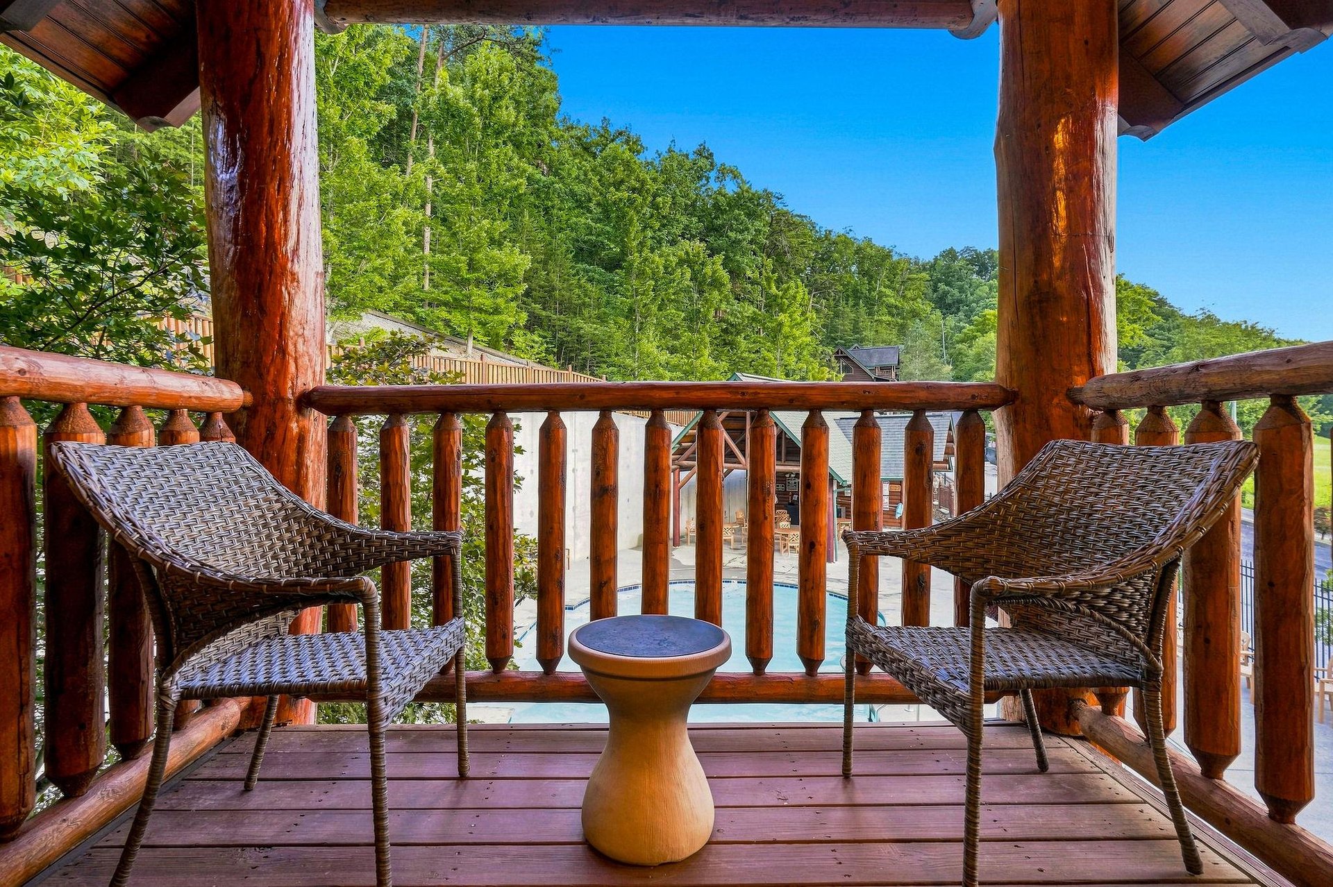 Picture yourself sipping morning coffee here, gazing at lush forested hills from your private covered balcony, where woven chairs and warm wood create an inviting mountain retreat.