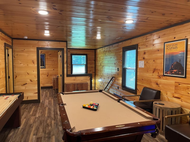 Step into your private game room with rich wood walls, pool table ready for play, and windows framing peaceful views. Perfect for friendly competition and laidback evenings.