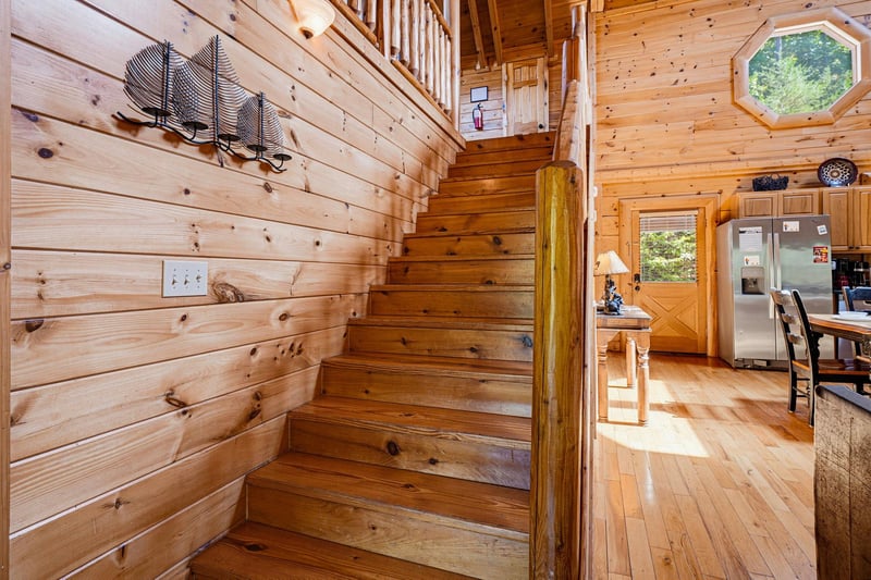 Sunlight pours through the cabins unique octagonal window, highlighting the warm wood staircase leading to your private loft retreat above.