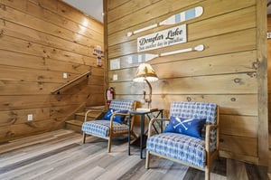 Settle into rustic charm with bluepatterned armchairs and warm wood walls that create your perfect lakeside retreat.
