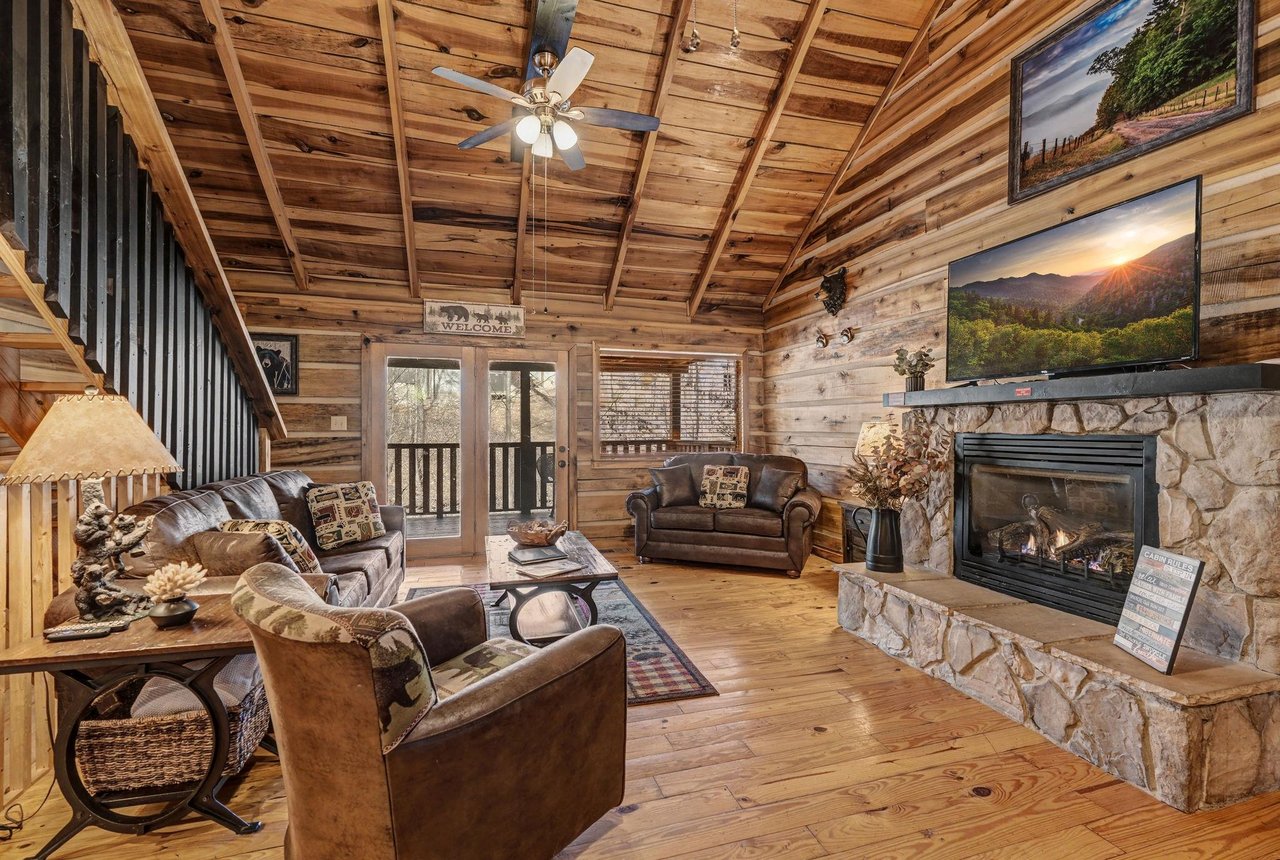 Unwind in your cozy log cabin retreat with exposed beam ceilings, crackling stone fireplace, and rustic leather seating that invites you to relax.