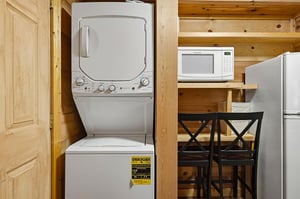 This space includes a stacked washer and dryer, microwave, and fridge—everything you need for a comfortable, selfsufficient stay in your home away from home.