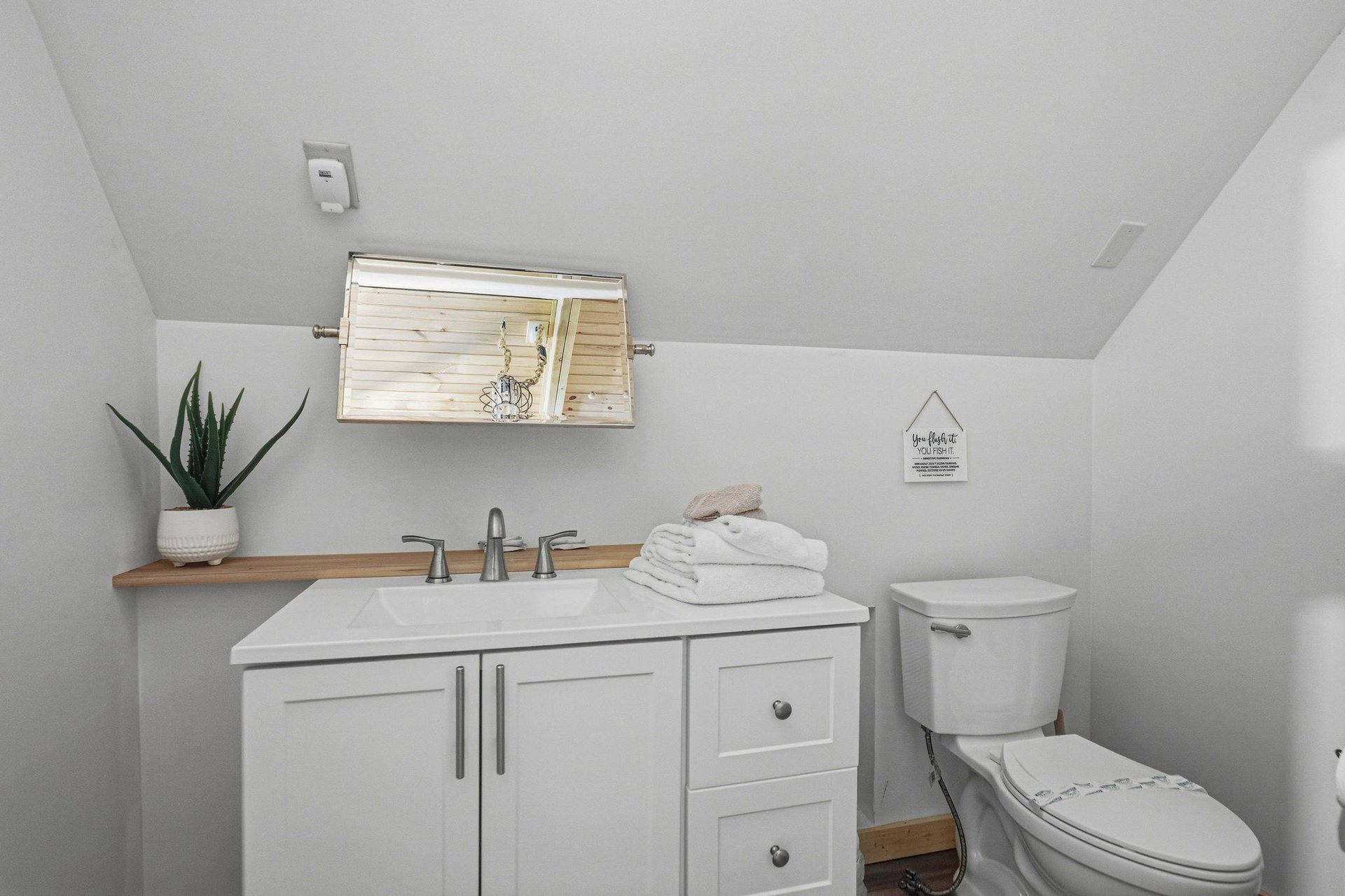 Your private bathroom offers clean comfort with plush white towels, modern fixtures, and thoughtful touches like a natural wood accent and fresh greenery to make you feel right at home.
