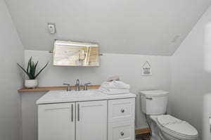 Your private bathroom offers clean comfort with plush white towels, modern fixtures, and thoughtful touches like a natural wood accent and fresh greenery to make you feel right at home.