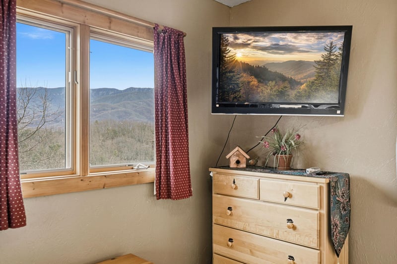 Your bedroom dresser sits beneath a stunning mountain sunset TV display, while your window frames sweeping valley views.