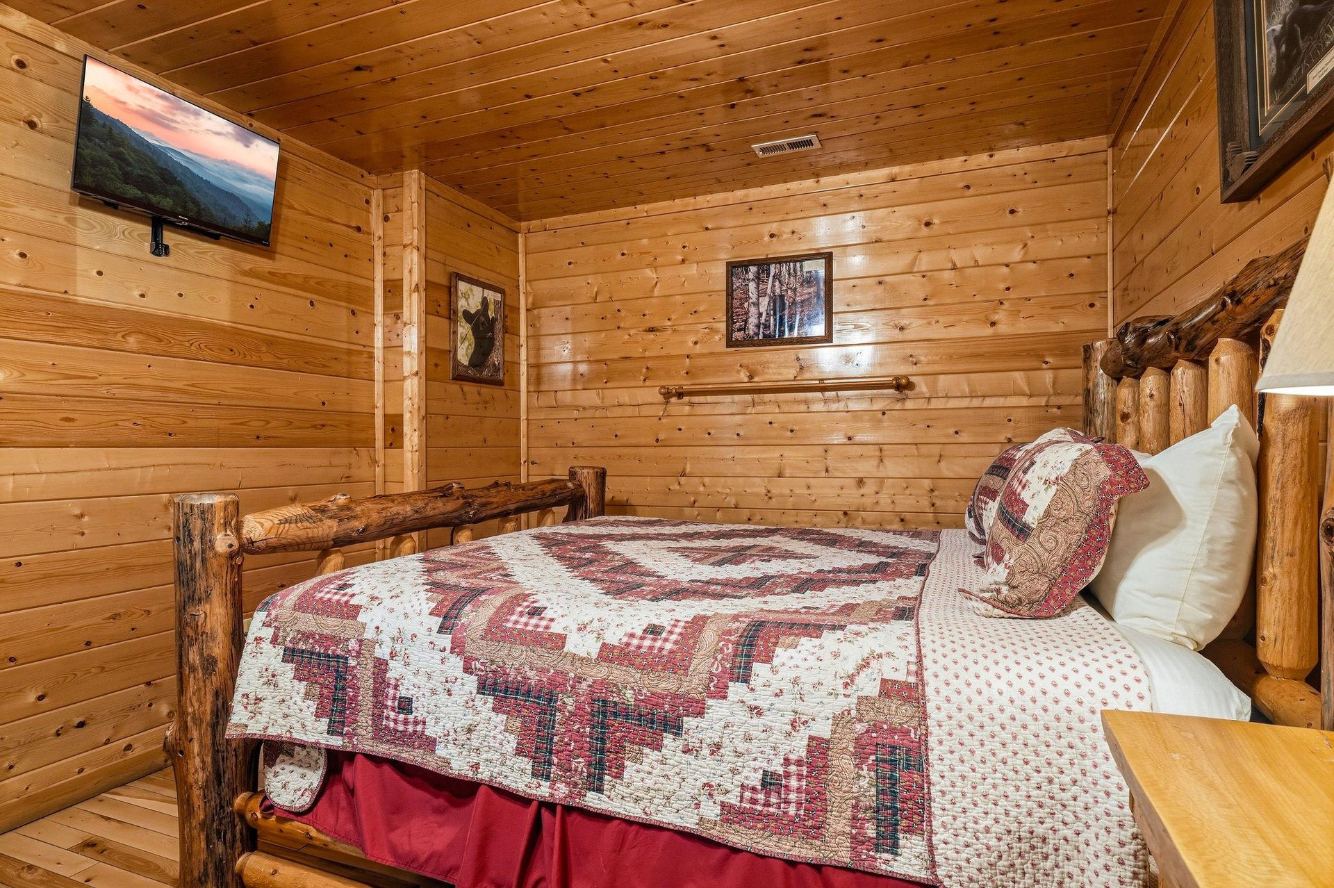 Sink into the warmth of this cozy cabin bedroom, wrapped in natural wood and rustic charm. Your handcrafted log bed awaits, inviting restful mountain nights beneath a quilted cover, with modern comfor