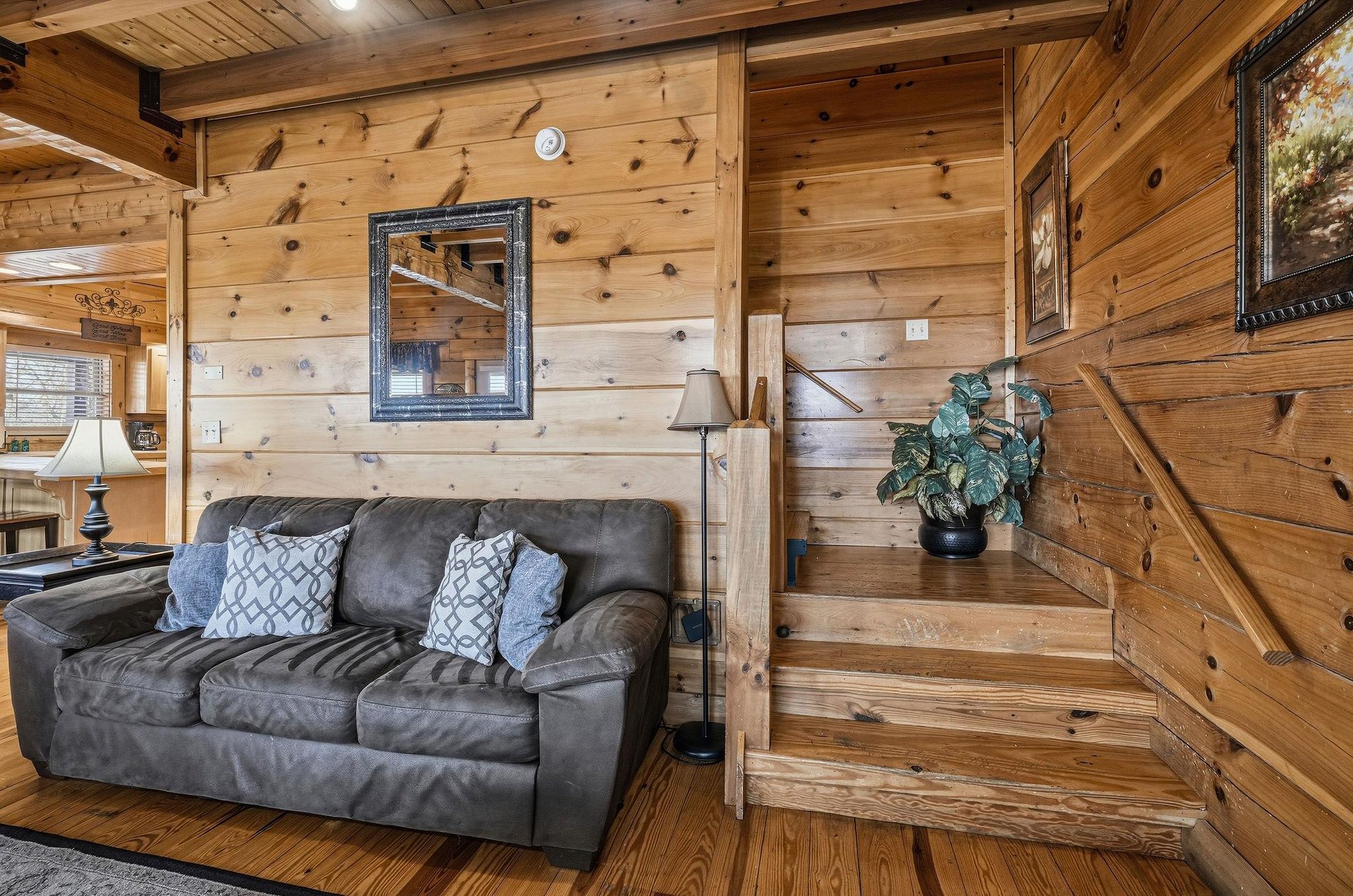 Sink into the plush leather sofa beneath rustic wood beams, where cozy pillows invite you to unwind in this charming cabin retreat.