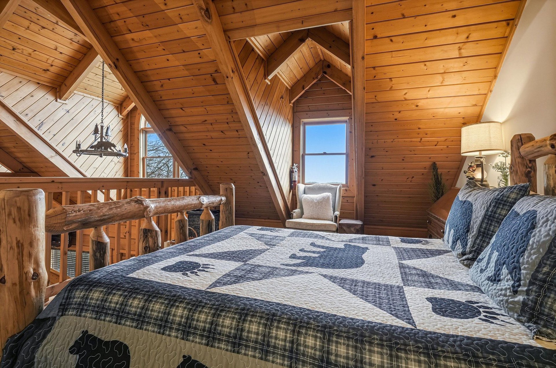 Drift off in your cozy loft bedroom, surrounded by warm wood beams and rustic charm, with peaceful views beyond.