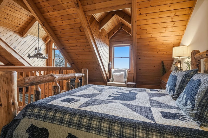 Drift off in your cozy loft bedroom, surrounded by warm wood beams and rustic charm, with peaceful views beyond.