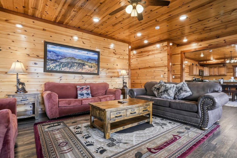 Unwind in your rustic living room where warm wood walls and cozy leather seating create the perfect mountain retreat atmosphere.