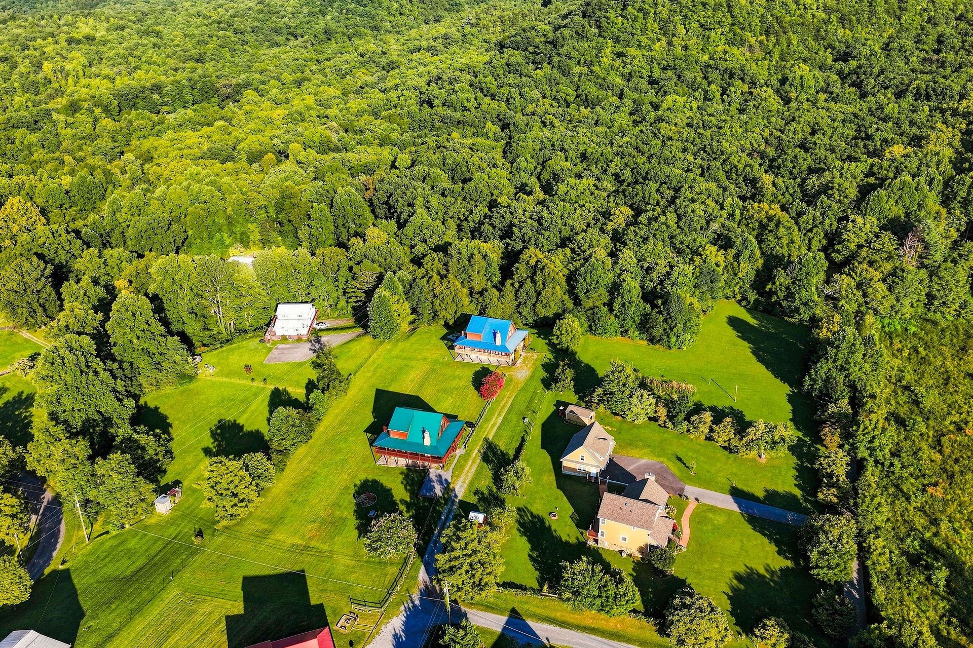 Aerial view of a secluded vacation property nestled among lush forests and open green lawns.