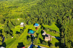 Aerial view of a secluded vacation property nestled among lush forests and open green lawns.