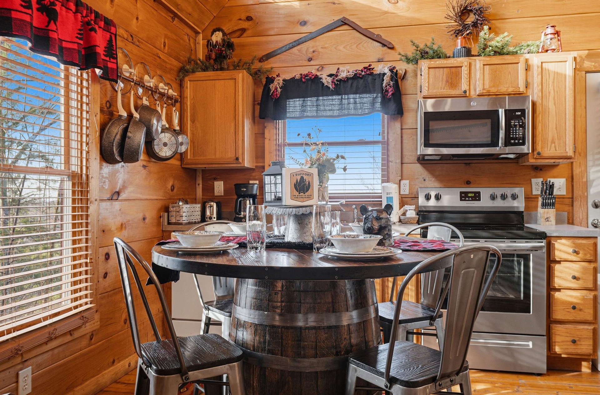 Your rustic cabin kitchen features warm wood walls, modern appliances, and charming barrel dining table perfect for intimate mountain meals.