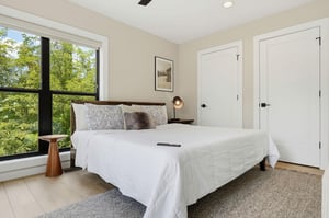 Wake to sunlight streaming through large windows framing lush greenery. Your plush bed invites restful nights while natural views create a serene, rejuvenating escape.
