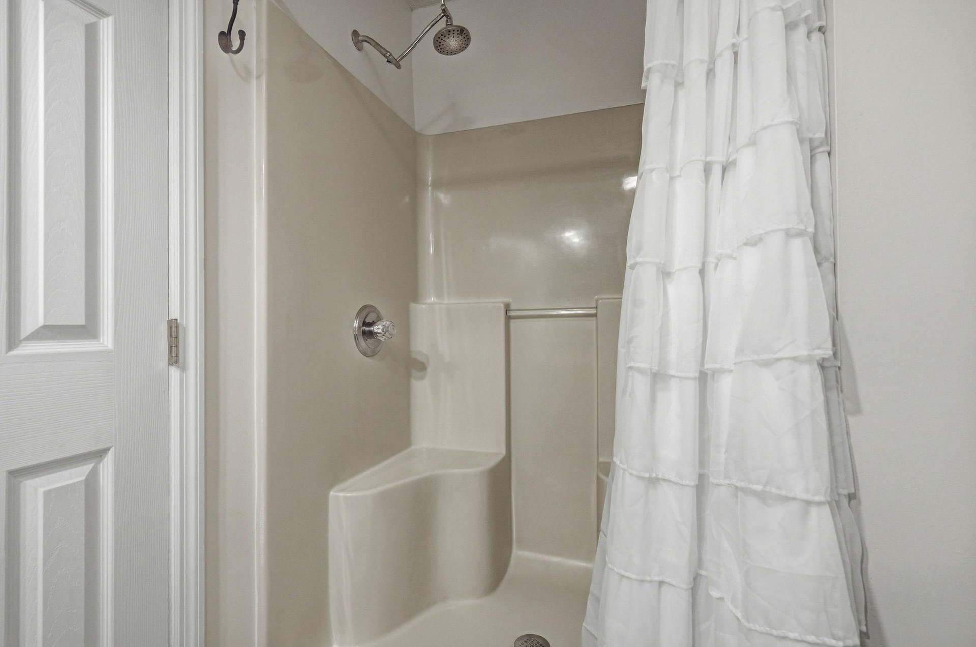 A clean, bright bathroom features a tubshower combo with dual showerheads and a crisp white curtain. Fresh towels await your arrival, ready for a refreshing rinse after a day of adventure.