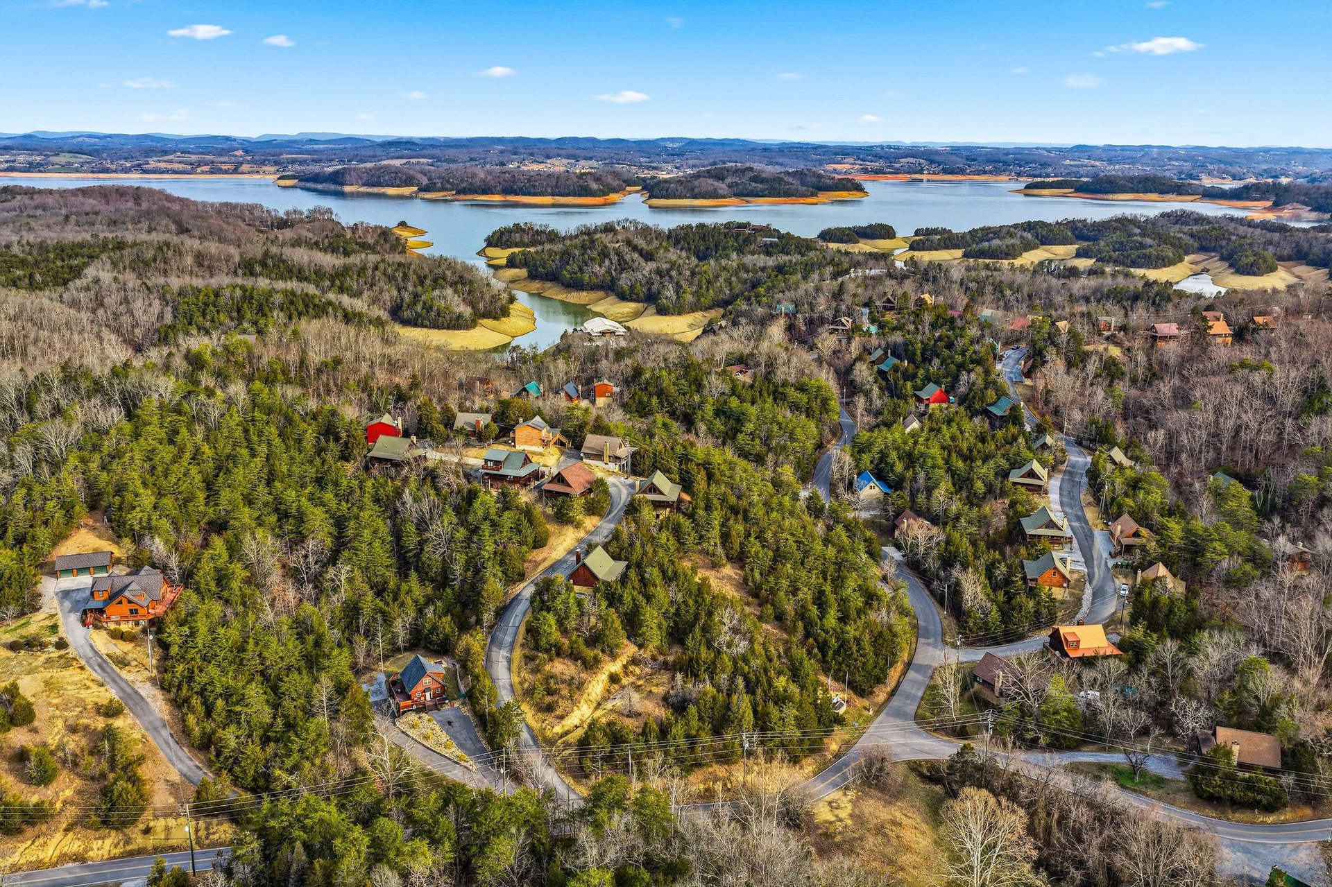 Aerial view of lakefront residential community nestled among forested hills and winding waterways.